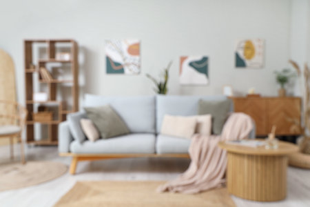 Interior of light living room with gray sofa, coffee table and pictures on wall, blurred viewの写真素材