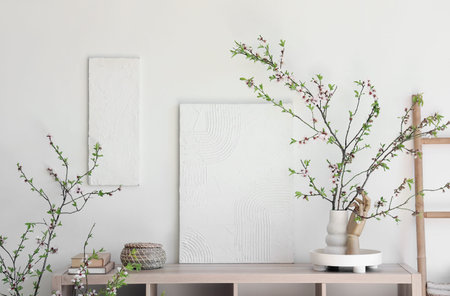 Table and vase with blooming branches in room