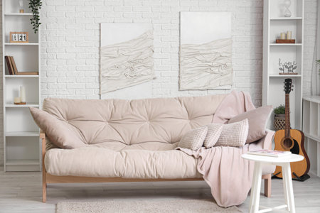 Beautiful interior of white living room with soft sofa, coffee table, acoustic guitar and pictures