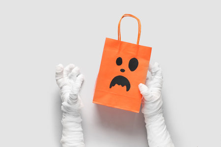 Mummy hands with shopping bag on gray background. Halloween celebrationの写真素材