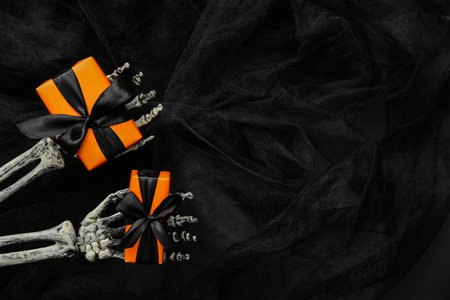Halloween gifts, skeleton hands and tulle on black background. Top viewの写真素材