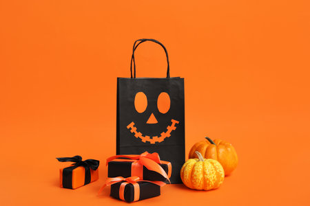 Shopping bag with Halloween gift boxes and pumpkins on orange backgroundの写真素材