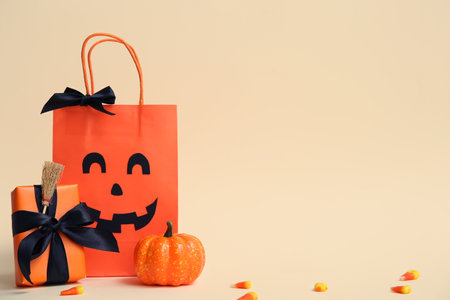 Shopping bag with Halloween gift and decorative pumpkin on beige backgroundの写真素材