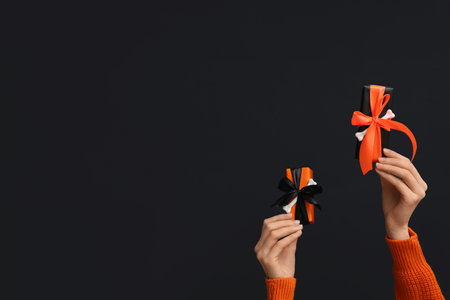 Female hands with Halloween gift boxes on black backgroundの写真素材
