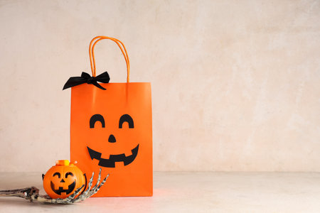 Composition with Halloween shopping package, skeleton hand and decorative pumpkin on light backgroundの写真素材