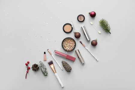 Beautiful Christmas decorations with different makeup products on gray backgroundの写真素材