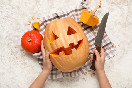 Woman holding carved pumpkin for Halloween and knife on white grunge backgroundの写真素材