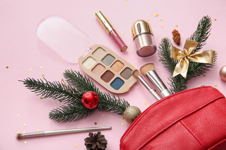 Beautiful Christmas decorations with fir branches, cosmetic bag and makeup products on pink backgroundの写真素材