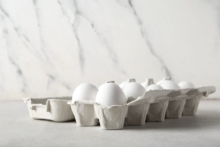 Holder with raw chicken eggs on white background
