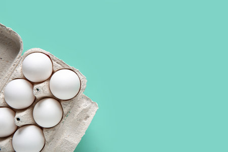 Holder with raw chicken eggs on turquoise backgroundの写真素材