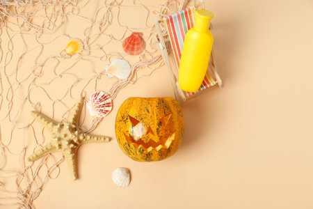 Halloween pumpkin with deckchair, sunscreen cream and starfish on beige backgroundの写真素材