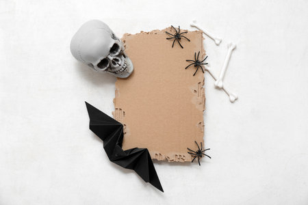 Composition with blank piece of cardboard and decorations for Halloween on light backgroundの写真素材