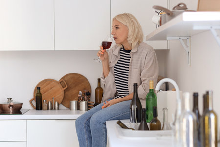 Mature woman drinking wine at home. Concept of alcoholismの写真素材