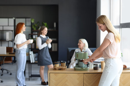 Young woman making coffee in officeの写真素材