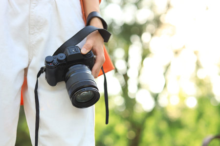 Young female photographer with modern camera in park, closeup