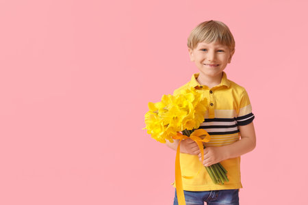 Cute little happy boy with bouquet of beautiful narcissus on pink background