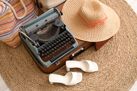 Suitcase with vintage typewriter and female accessories on wicker rugの写真素材