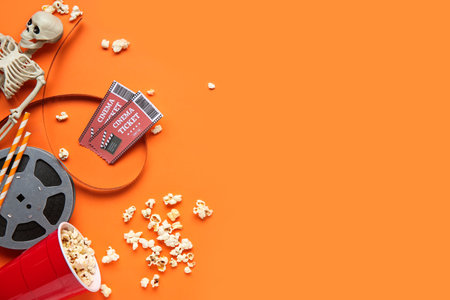Composition with popcorn, film reel, cinema tickets and skeleton for Halloween on color backgroundの写真素材
