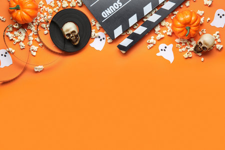 Composition with film reel, clapperboard, popcorn and decorations for Halloween on color backgroundの写真素材