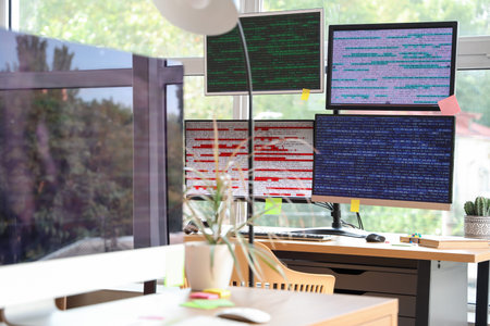 Computer monitor with code and plant on programmer's desk in office