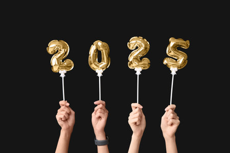 Female hands with figure 2025 made of foil balloons on black background