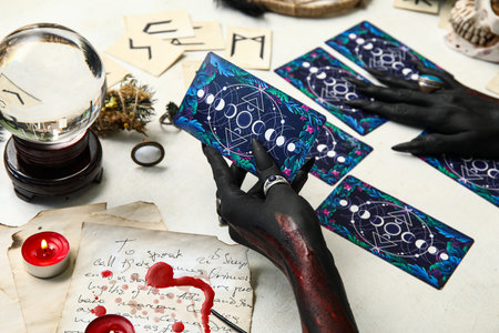 Bloody black witch hands with tarot cards and magic attributes on grunge white background. Halloween celebrationの写真素材