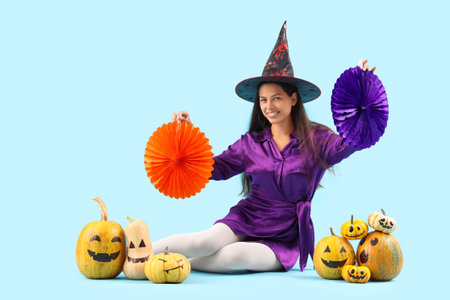 Young woman with Halloween pumpkins on blue background