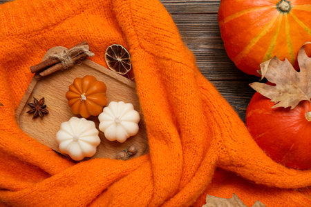 Composition with autumn candles, stylish warm sweater and pumpkins on wooden backgroundの写真素材