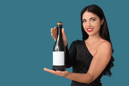 Beautiful young happy woman with bottle of champagne on blue backgroundの写真素材