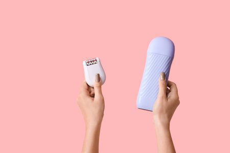 Female hands with liposoluble wax cartridge and epilator on pink background. Depilation conceptの写真素材