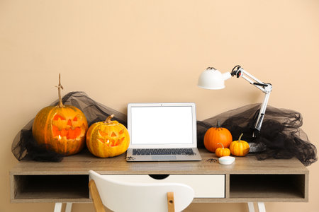 Workplace with laptop and pumpkins in comfortable office interior decorated for Halloween celebrationの写真素材