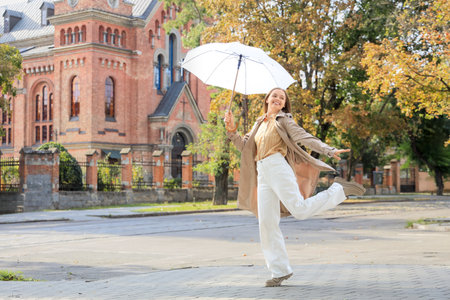 Happy young woman with umbrella on city streetの写真素材