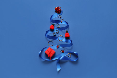 Christmas tree made of stylish jewellery, ribbon and decorations on blue backgroundの写真素材