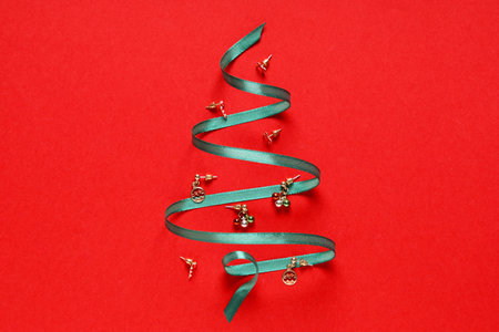 Christmas tree made of stylish jewelry and ribbon on red background