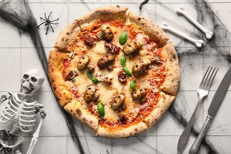 Tasty pizza with mushrooms, bones and skeleton for Halloween celebration on white tile backgroundの写真素材