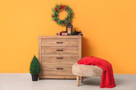 Christmas decorations and gift boxes on commode near yellow wall at home