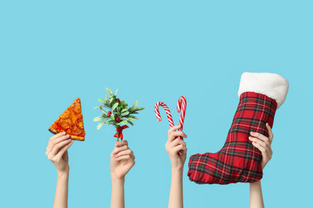 Female hands with pizza slice, Mistletoe branch, candies and Christmas sock on blue background