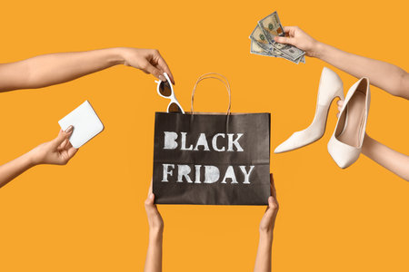 Hands with shopping bag, money and accessories on yellow background. Black Friday saleの写真素材