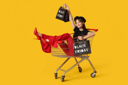 Young woman with bags in shopping cart on yellow background. Black Friday Sale