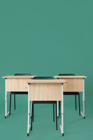 School desks with chairs on green background