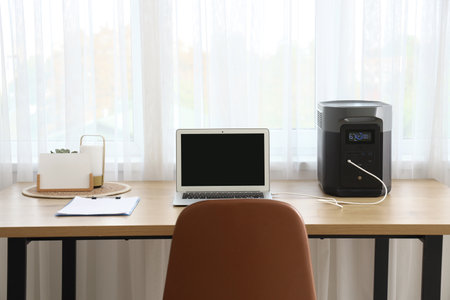 Portable power station charging laptop on table in officeの写真素材