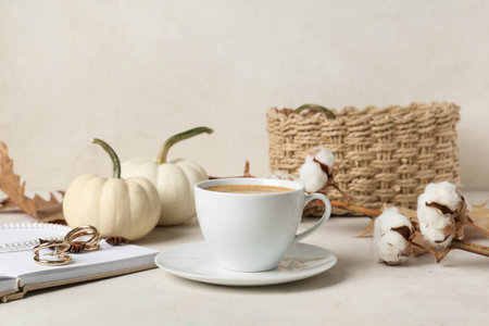 Cup of tasty pumpkin coffee with autumn decorations and jewelery on white grunge backgroundの写真素材