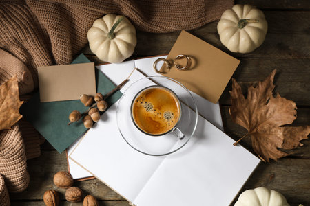 Cup of tasty pumpkin coffee with autumn decorations, warm sweater and books on brown wooden...
