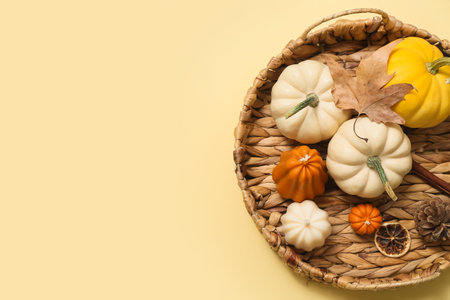 Wicker tray with ripe pumpkins and autumn candles on color backgroundの写真素材