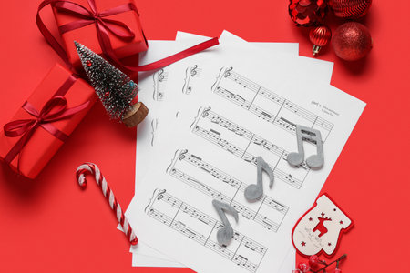 Composition with music sheets, Christmas gifts and decorations on red backgroundの写真素材