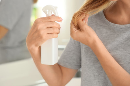 Mature woman applying hair care product in bathroom, closeupの写真素材