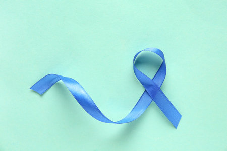 Blue ribbon on turquoise background. World Cancer Day