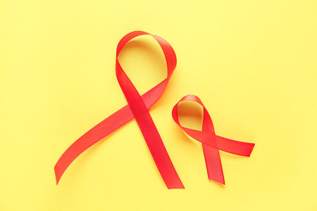 Red ribbons on yellow background. World Cancer Dayの写真素材