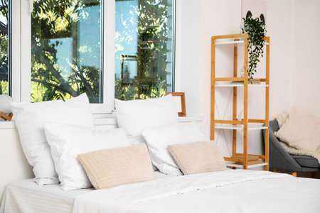 Soft pillows on bed in light bedroomの写真素材