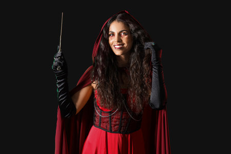 Young witch with magic wand on dark backgroundの写真素材